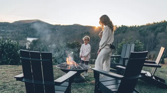 A family around the fire pit at dusk, mountains behind